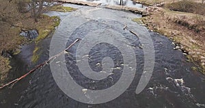 4K Aerial view of wild river in forest. Water runs over rocks.