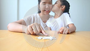 4K Asian little girl playing jigsaw puzzle with mother