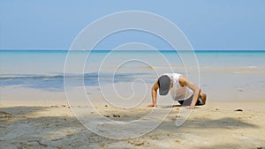 4K. athletic man workout by  push up at the sandy beach, part of his cross fitness workout.