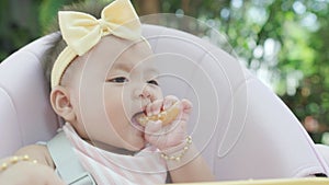 4k Baby infant daughter toddler eating on highchair in a garden