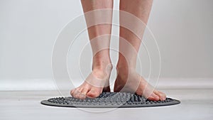 4K. Bare girlish feet trample orthopedic massage mat. Prevention of diseases.