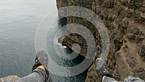 4K Beautiful view of Traelanipan, Legs Man Sitting Edge Cliff in Vagar, Faroe