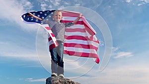 4k. Blonde boy waving national USA flag outdoors over blue sky at summer - american flag, country, patriotism