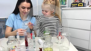 4K, Close-up of colored science test tubes with a blurry background of two children having fun mixing colors in a school