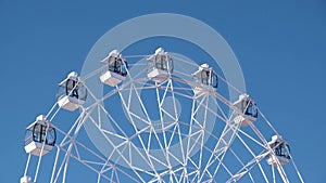 4K. close-up of a white Ferris wheel slowly rotating against the blue sky on a sunny day.