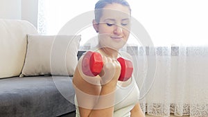 4k closeup footage of young smiling woman exercising and strenghtening hand muscles with dumbbells
