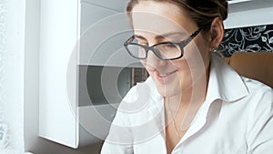 4k closeup video of young smiling businesswoman wearing eyeglasses working at office and looking at computer screen