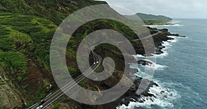 4K Drone Coastal Roadway Rocky Shore Crashing Waves Mountainside Flying Backwards