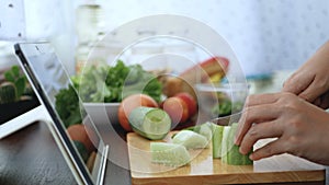 4K. female hand cut and slice cucumber, prepare ingredients for cooking follow cooking online video clip on website via tablet.