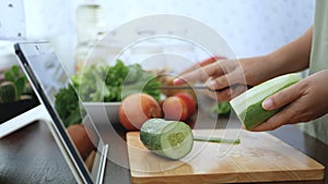 4K. female hand slicing cucumber peel, prepare ingredients for cooking follow cooking online video clip on website via tablet.