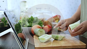 4K. female hand slicing cucumber peel, prepare ingredients for cooking follow cooking online video clip on website via tablet.