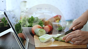 4K. female hand slicing cucumber, prepare ingredients for cooking follow cooking online video clip on website via tablet. cooking