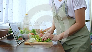 4K. female hand slicing fresh lettuce, prepare ingredients for cooking follow cooking online video clip on website via tablet.