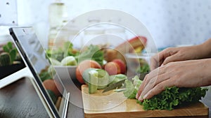 4K. female hand slicing green vegetable, prepare ingredients for cooking follow cooking online video clip on website via tablet.