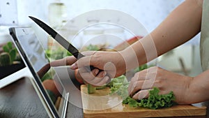 4K. female hand slicing green vegetable, prepare ingredients for cooking follow cooking online video clip on website via tablet.