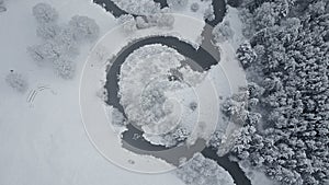 4K. Flight above clouds and wild winding river in frozen forest. Snowly winter on the north. Aerial panoramic view