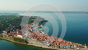 4K. Flight over old city Piran in the morning, aerial panoramic view with old houses, Tartini Square, St. George`s Parish Church.