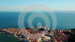 4K. Flight over old city Piran in the morning, aerial panoramic view with Tartini Square, St. George`s Parish Church and marina.
