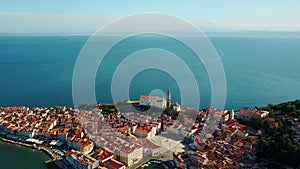 4K. Flight over old city Piran in the morning, aerial panoramic view with Tartini Square, St. George`s Parish Church and marina.