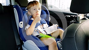 4k footage of 3 years toddler boy sitting in child car safety seat and eating