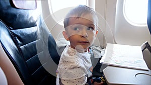 4k footage of adorable 2 years old toddler boy looking in airplane illuminator during flight