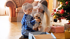 4k footage of adorable little boy opens his present box from Santa Claus and taking out toy plush dog. Family giving and