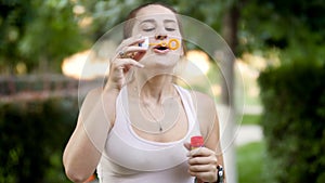 4k footage of beautiful smiling young woman making soap bubbles in park at sunset