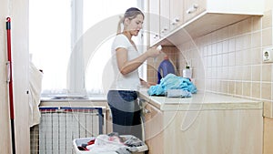 4k footage of beautiful young woman smelling dirty sock and throwing it in basket at laundry