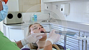 4k footage of dentist putting on protective glasses and using UV lamp while curing patient`s teeth with photopolymer