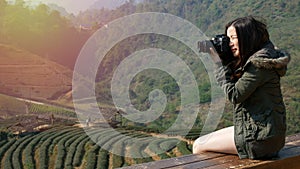 4K footage of happy Asian tourist woman taking photo of beautiful nature from tea field plantation in Asia by digital camera