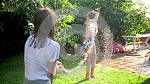 4k footage of happy laughing family playing with water guns and garden hose on grass at house backyard