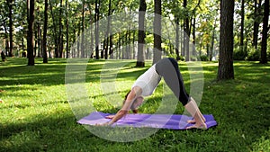 4k footage of happy smiling woman stretching on fitness mat at park. Middle aged lady doing yoga exercises at forest.