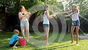 4k footage of happy young family playing with water guns on grass at backyard