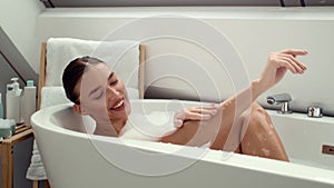 4K footage: Joyful woman in foamy bath, washing hands and playing with bubbles