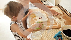 4k footage of little boy helping his mother cooking pie with cherries