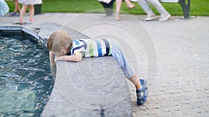 4k footage of little toddler boy playing in fountain at park