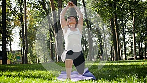 4k footage of middle aged woman exercising in park. Adult female practising yoga on fitnes mat at forest