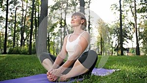 4k footage of middle aged woman exercising in park. Adult female practising yoga on fitnes mat at forest