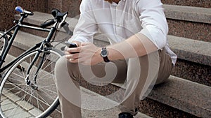 4k footage of smiling hipster red bearded man sitting on stone staricase with mobile phone