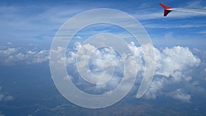 4K footage. Traveling by air. Aerial view through an airplane window. Wing airplane and beautiful white clouds in blue sky