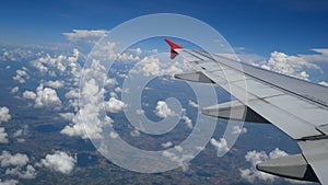 4K footage. traveling by air. aerial view through an airplane window. wing airplane and beautiful white clouds in blue sky