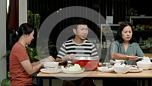 4k, A group of 3 Asian friends are eating sukiyaki in a restaurant in front of them with sukiyaki condiments and red sukiyaki pots