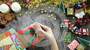 4K. hands take a gift box for Christmas present out of the shopping bag  on a table with Christmas ornaments decoration.