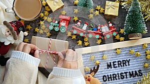 4K. hands tie a bow in a rope on kraft paper sheets for Christmas gift box present on a table with Christmas ornaments decoration