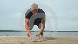 4k of Handsome young man doing push-ups outdoors during training at lake