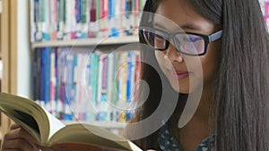 4K : Little Asian students reading a book in library