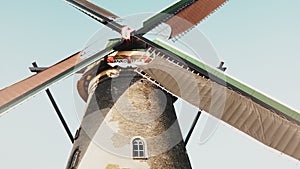 4K Low angle view of traditional old windmill. Netherlands. Dutch historical heritage. Rustic farm mill spinning slowly.