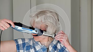 4K. A middle-aged woman independently dries and styles her hair with a hair dryer at home.