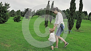 4k Mother playing with her little one year old blue eyed pretty son in green grass park full of trees