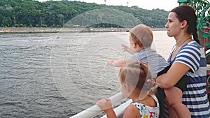 4K. Mother with two children are floating on a boat on the wide river of the Dnieper and look overboard